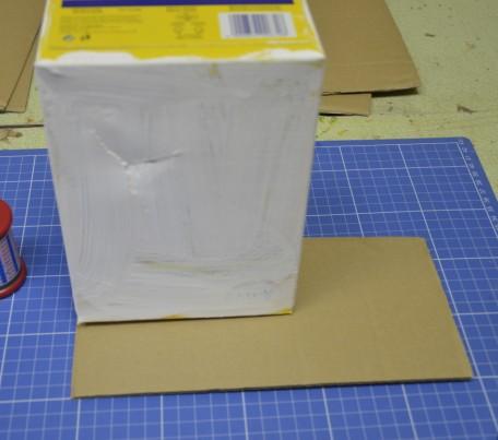 Spodek krabice (tak, jak bude budka stát) se položí na kus kartonu. Tužkou si můžeme naznačit přesahy.