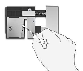 3 Zasuňte narovnanou sponku na papíry (nebo jiný špičatý předmět) do malého otvoru (viz Obrázek 13) auvolněte řezací mechanismus.