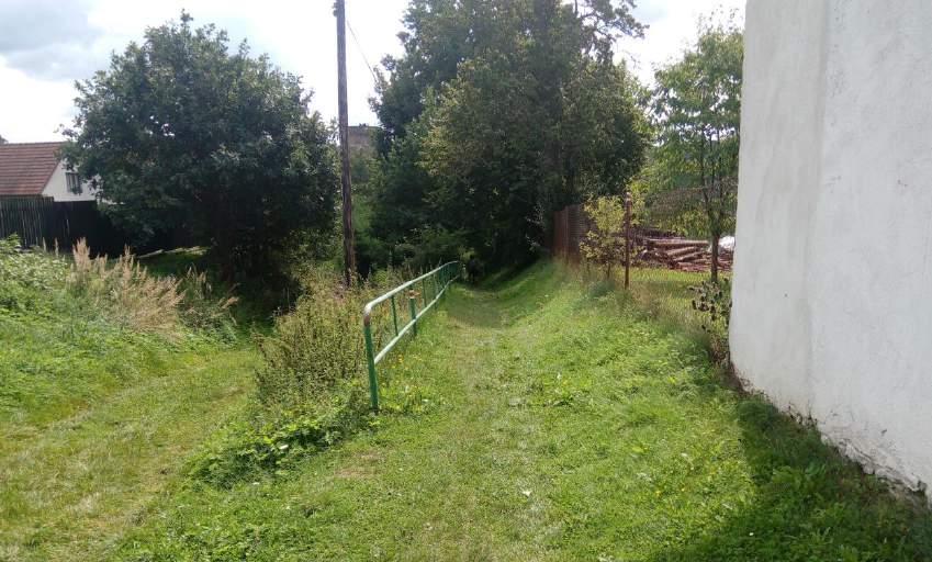 Cesta k památce Za místní komunikací následuje rozvětvená travnatá cesta.