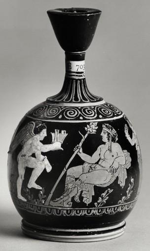 Kat. č.: II/10 Objekt: attický červenofigurový lekythos Autor: Makariův malíř Datace: cca 400 př. n. l. Materiál: terakota, zlato Popis: Dionýsos vyobrazený jako krásný nahý mladík sedí na plášti.