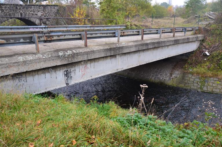 Hluboké obdélníkové koryto je opevněno kamennými zdmi (Foto 3.17). Koryto Chomutovky zde křižuje nejprve lávka pro pěší M25 v ř. km 31.