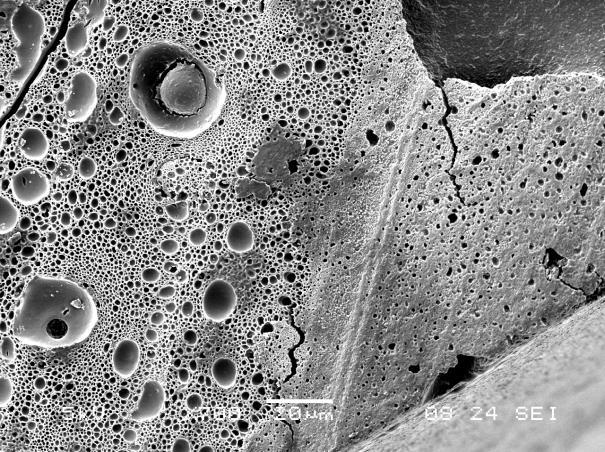 spodině výplně v kontaktu s dentinem, b) detail stěny kompozitní výplně s patrnými bublinkami různé velikosti, zvětšení 270 a 700 x, SEM a) b) Obr.