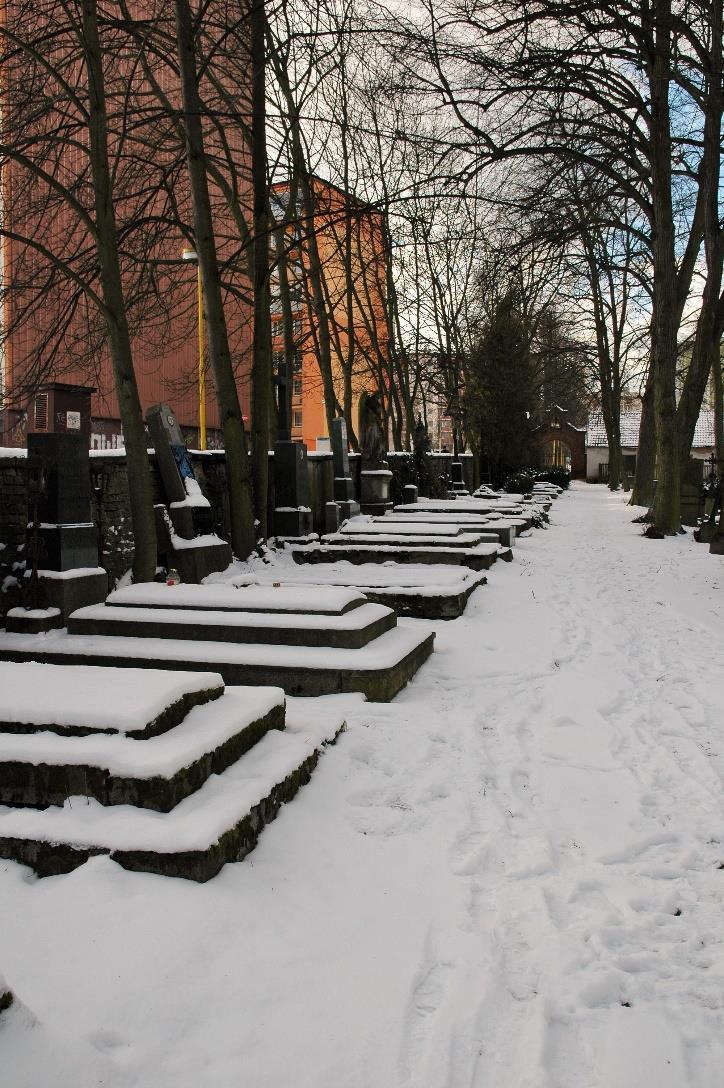 Čestná řada hrobek vpravo od původního vchodu u kdysi bílé, nyní rozvalené zdi Zde odpočívají rodiny těch, kteří se