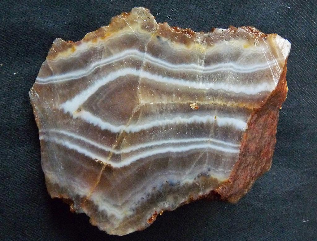Část žiloviny tvoří šedomodrý chalcedon, poměrně často se zajímavou achátovou texturou v akumulacích o velikosti do cm (obr. 7 a ).