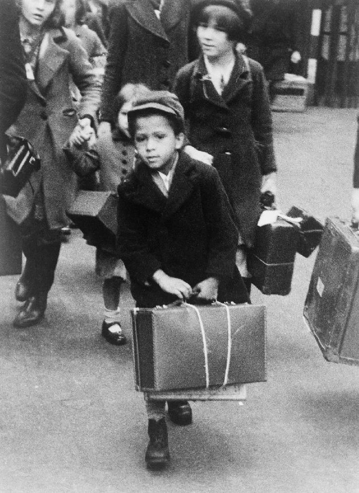 Evakuovaní Fotografie zachycuje malého chlapce s kufrem, který se skupinou dalších evakuovaných odjíždí 5. července 1940 z Londýna na venkov.