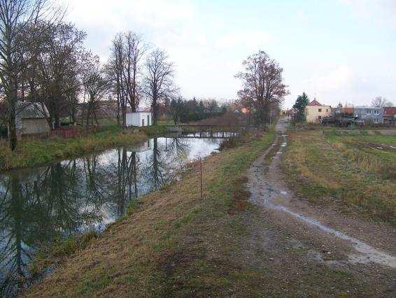 Pohled na tok Loučné pod přemostěním ve směru na jez (vlevo odbočuje náhon).
