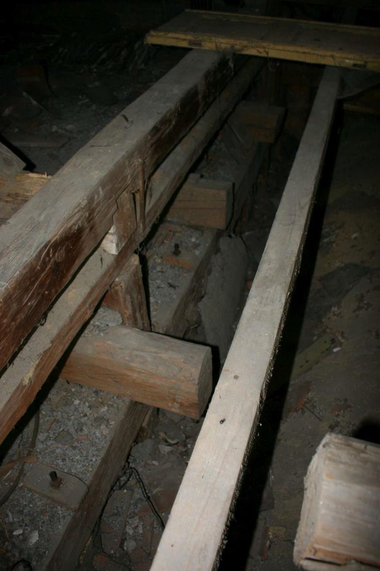 Prvky dřevěných nosníků jsou napadené hnilobou a jsou usmyknuté v uložení na zdivu, konstrukce ocelového závěsu je zcela labilní, takže je nutné celou komplikovanou konstrukci odstranit a nahradit